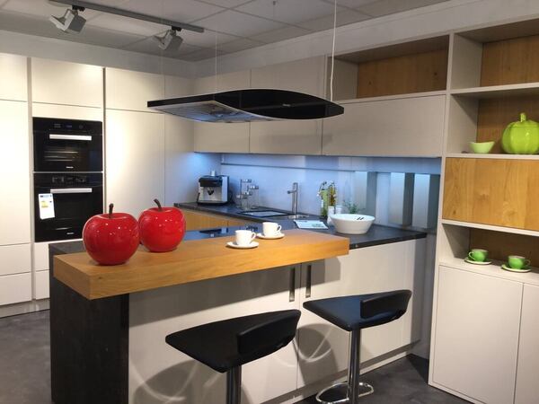 Moderne Einbauküche mit Kücheninsel, Barhockern und dekorativen roten Apfel-Objekten.